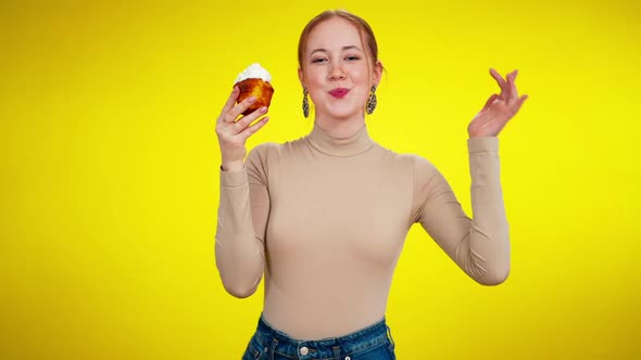 Middle Shot Portrait of Cheerful Slim Young Redhead Woman Tasting Topping From Small Cake Looking at