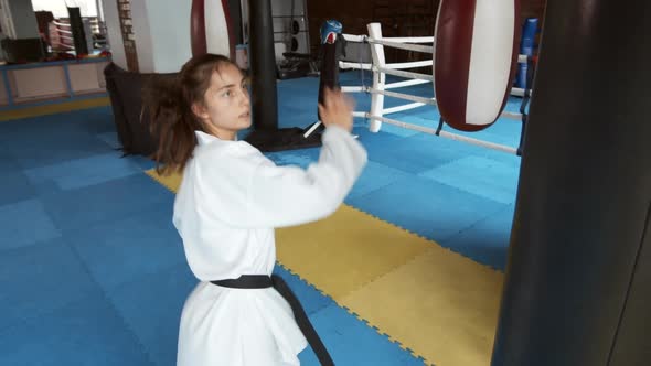 Girl in Kimono Exercising with Punching Bag