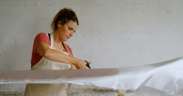 Woman cutting fabric for surfboard 