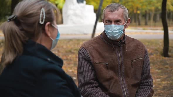 Senior Grandparents Couple in Medical Masks Sitting in Park