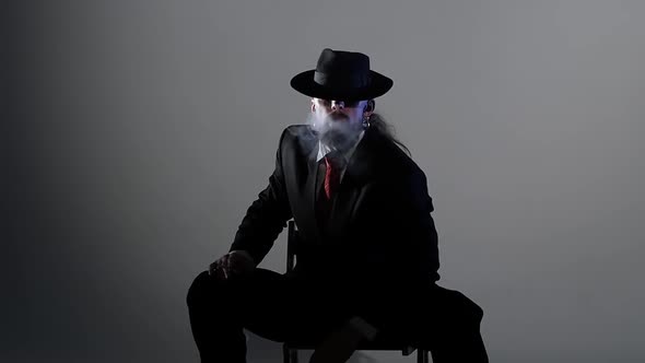 Elegant Man in a Black Hat Is Dancing an Erotic Dance. Spotlight on a Black Background. Close Up