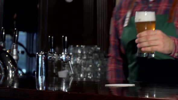 Bartender Pouring Glass of Delicious Tasty Beer at Pub, Placing It on the Counter
