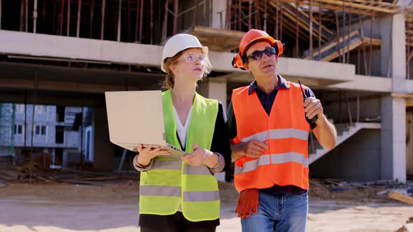 Young Engineer Lady with a Laptop Walking Beside