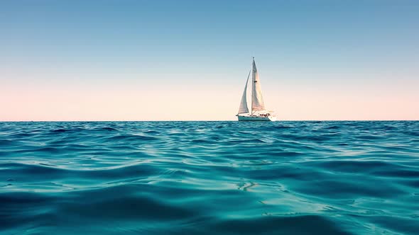 Extreme low-angle view of small white yacht boat sailing slowly in calm open ocean