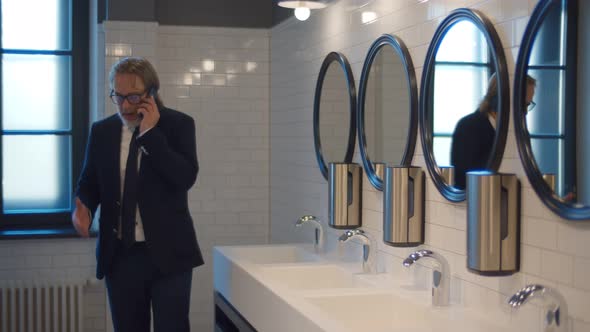 Senior Businessman Talking on Smartphone in Public Restroom