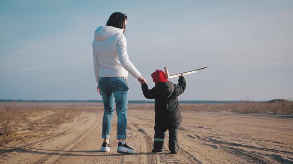 Happy Mother with Little Son Playing with Toy Plane at Sunset. Attractive Mother and Child Hugging