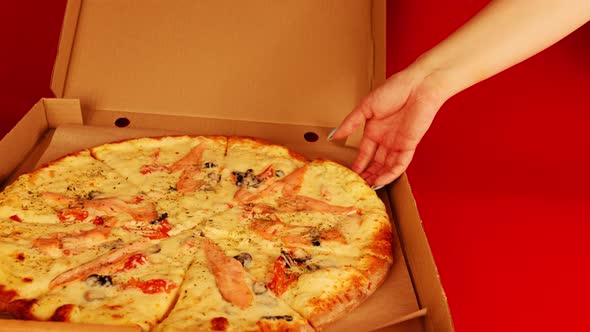 Appetizing large pizza in box on red background.