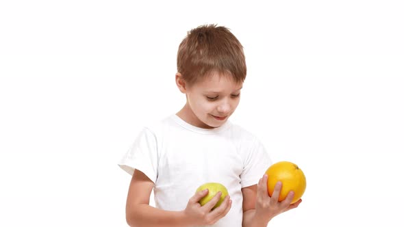 Elementaryaged Caucasian Boy Closely Inspecting Apple and Orange in His Hands Then Choosing Last One