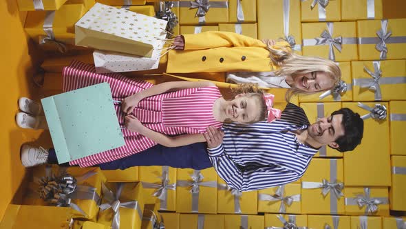 Happy Caucasian Family with Their Daughter Holding Colorful Shopping Bags and Happily Posing in