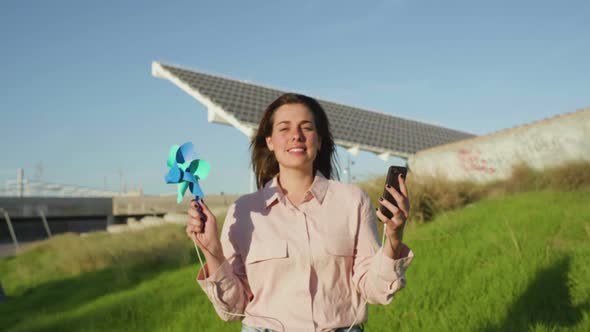 Slow motion shot of young woman with pinwheel and smartphone