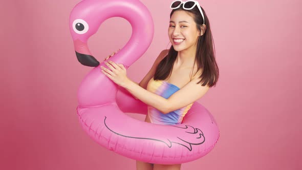 Beautiful Sexy asian woman in bikini and smiling standing  on pink background