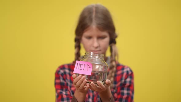 Help on Aquarium Bottle with Little Fish in Hands of Blurred Teenage Girl at Yellow Background