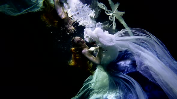 Stunning Woman is Floating Underwater Wearing Long Silk Dress Swaying in Water Female Silhouette