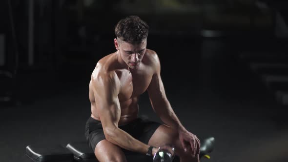 Athletic Man Trains in the Gym Lifts Dumbbells and Performs Exercises for the Arms and Biceps