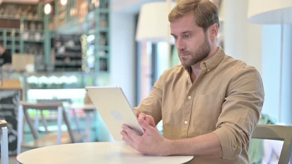 Attractive Young Man with Digital Tablet in Cafe