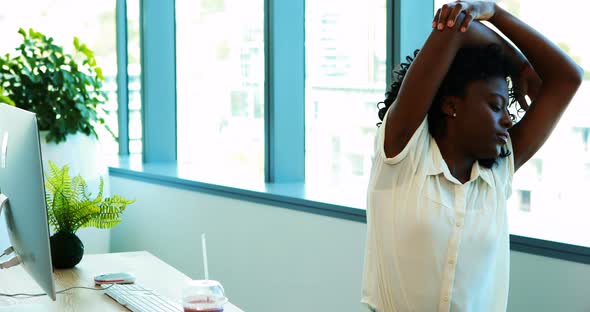 Female executive doing stretching exercise while working at her desk