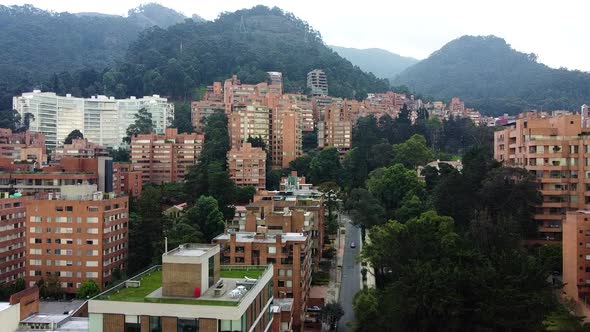 Drone up shot of city landscape showing mountains, trees and buildings