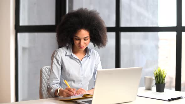 A Young Biracial Woman Is Using a Laptop Indoor