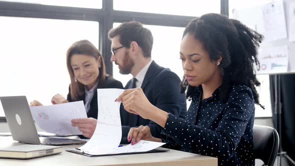 Young Pretty Positive African American Business Woman Sitting at the Workplace in Modern Office