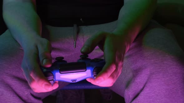 Closeup of Young Man Hands Playing Video Games on Gaming Console in Front of TV Widescreen