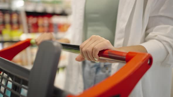 Woman Holding Grey Cart Does Shopping in Supermarket