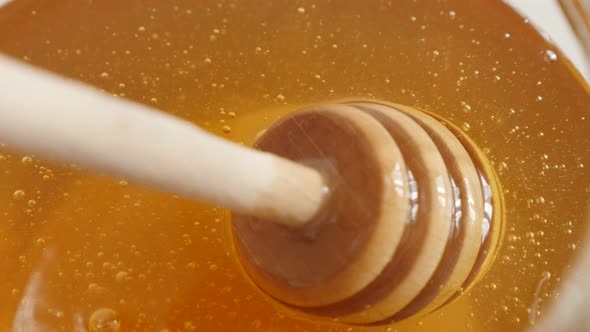 Close-up of spiral spoon  dipped in glass honey jar 4K 2160p 30fps UltraHD footage - Wooden  dipper 