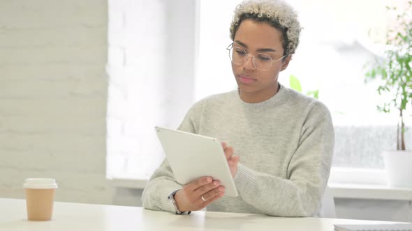 African Woman Celebrating Success on Tablet in Office