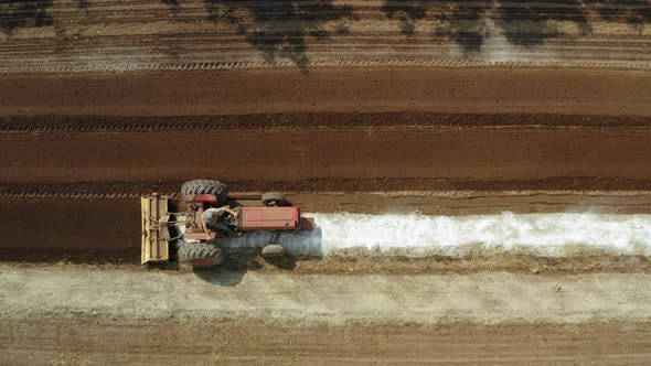 Tractor mixing fertilizer with the crop land, aerial drone shot of amending machine in the field