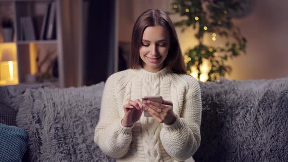 Smiling Brunette Using Smartphone at Home