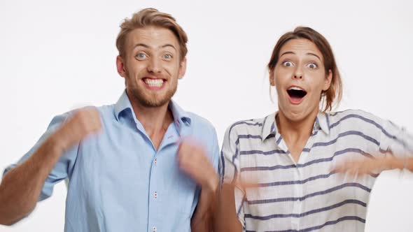 Young Caucasian Couple on White Background Unexpectedly Winning and Actively Rejoicing