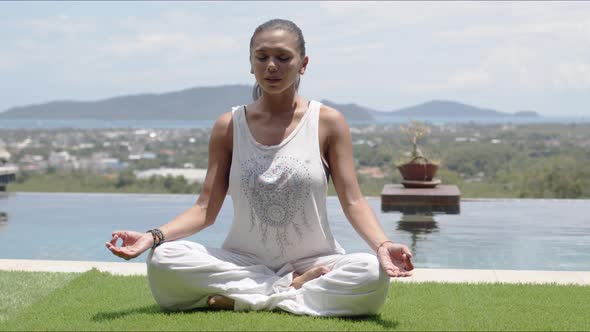 Lady Practicing Yoga in Lotus Pose Against Ocean Coast