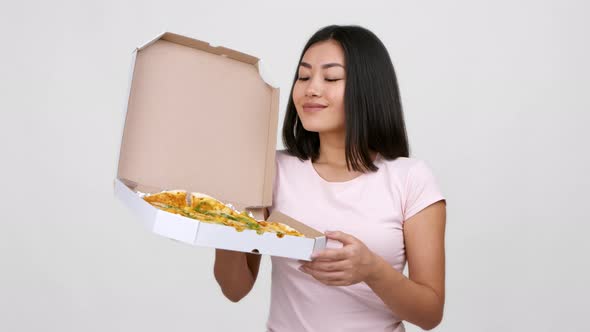 Asian Woman Holding Pizza Box Gesturing ThumbsUp Over White Background