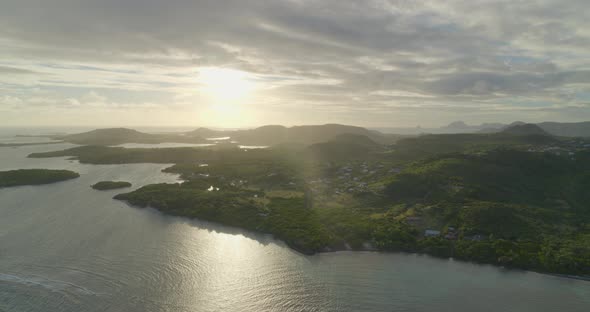 Aerial of bright sunlight over green coast and calm sea, Cap Chevalier