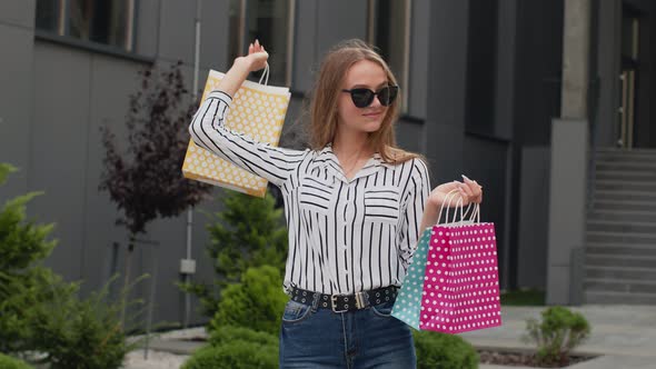 Girl Raising Shopping Bags, Looking Satisfied with Purchase, Enjoying Discounts on Black Friday