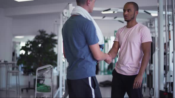 African American Guy Shakes Hands with a Caucasian Guy in the Gym Two Young Guys in the Gym People