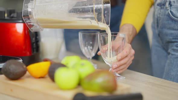 Unrecognizable Husband Pouring Milkshake in Glasses As Woman Waiting for Healthful Drink