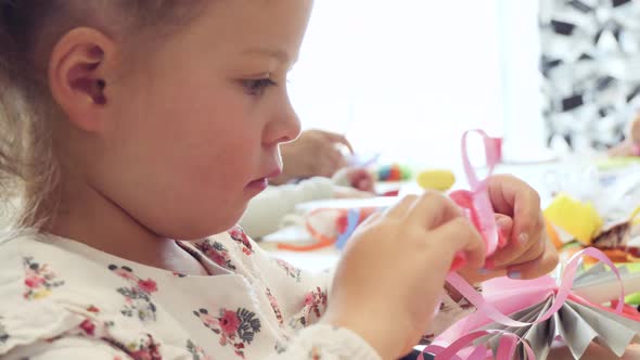 Little girl making paper butterflies from multicolor paper.