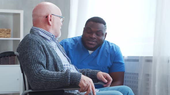 African-American caregiver and old disabled man in a wheelchair. Nurse and handicapped patient.