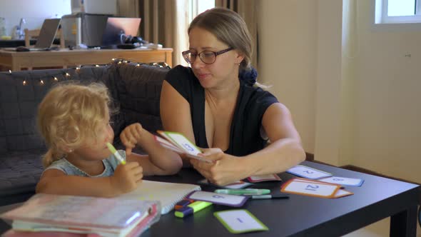 A Teacher, a Tutor for Home Schooling. a Teacher or Mom at the Table with a Little Girl