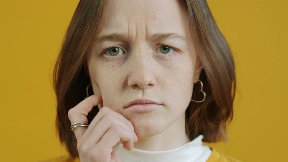 Portrait of Thoughtful Young Woman Looking at Camera Touching Face Thinking Over Problem Making