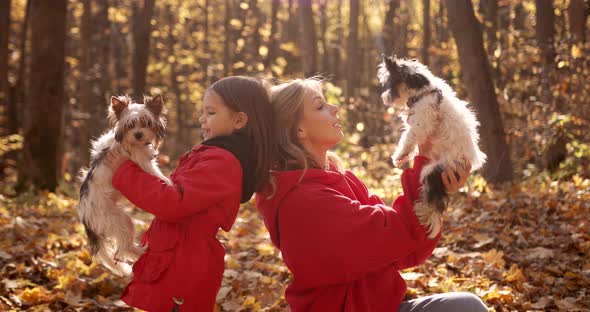 Mother and Daughter Playing with Dogs in the Forest