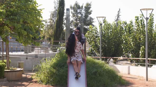 Young Multiethnic Hipster Women Having Fun on Playground Slide Outdoors