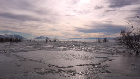 Flying over frozen lake with cracked ice on the surface