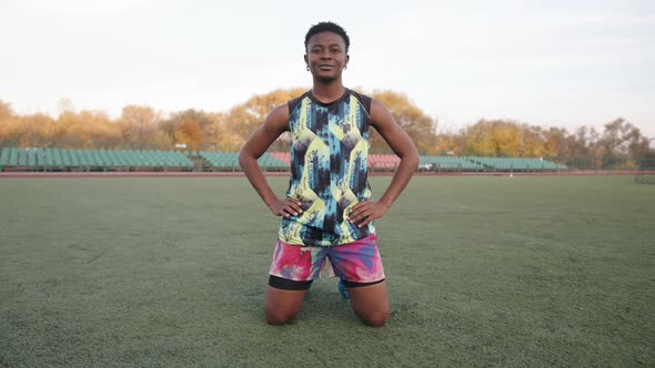 Young Black Girlin Bright Sports Uniform Training on the Soccer Field and Doing Forearm Stretching