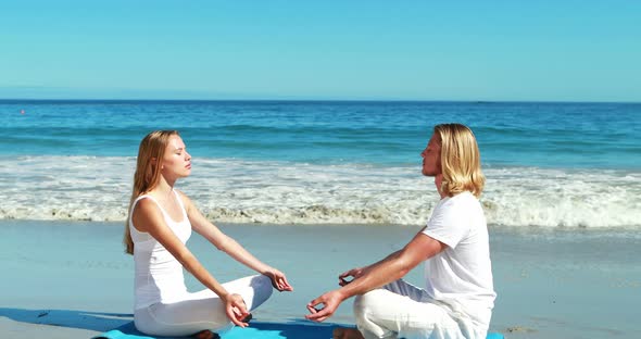 Couple performing yoga at beach