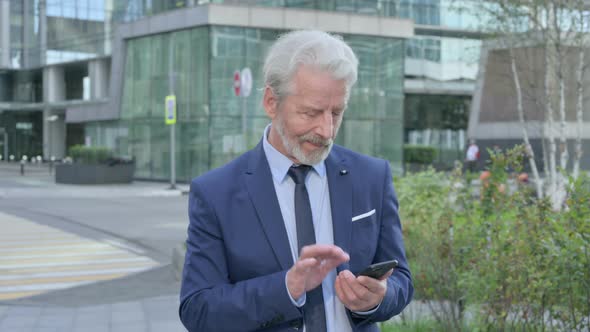 Walking Old Businessman Using Smartphone