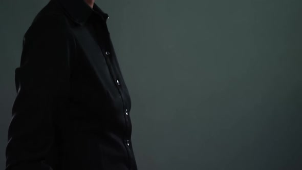 Androgynous man in suit posing against dark background