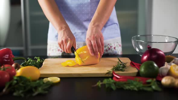 Young Woman Slicing Yellow Pepper in the Kitchen