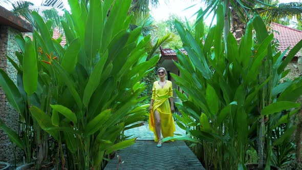 Asian Woman in Yellow Dress Walks Through Green