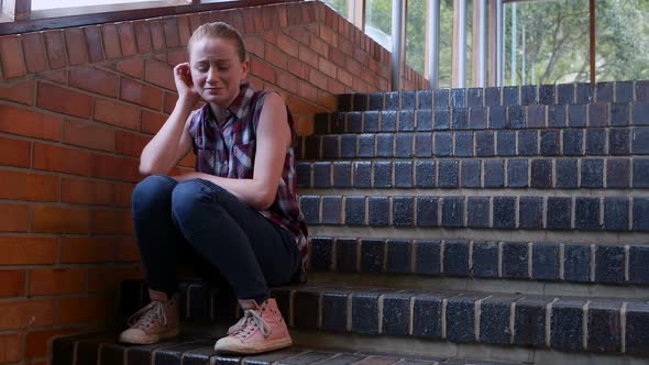 Sad schoolgirl sitting alone on staircase